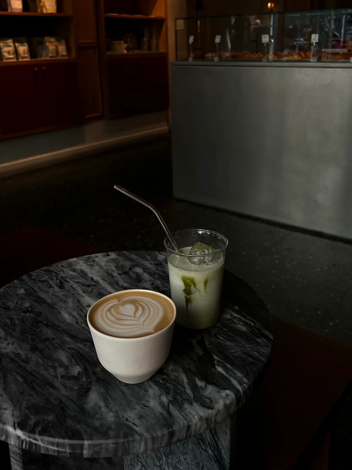 Un café con leche y un matcha con hielo sobre una mesa de mármol oscuro
